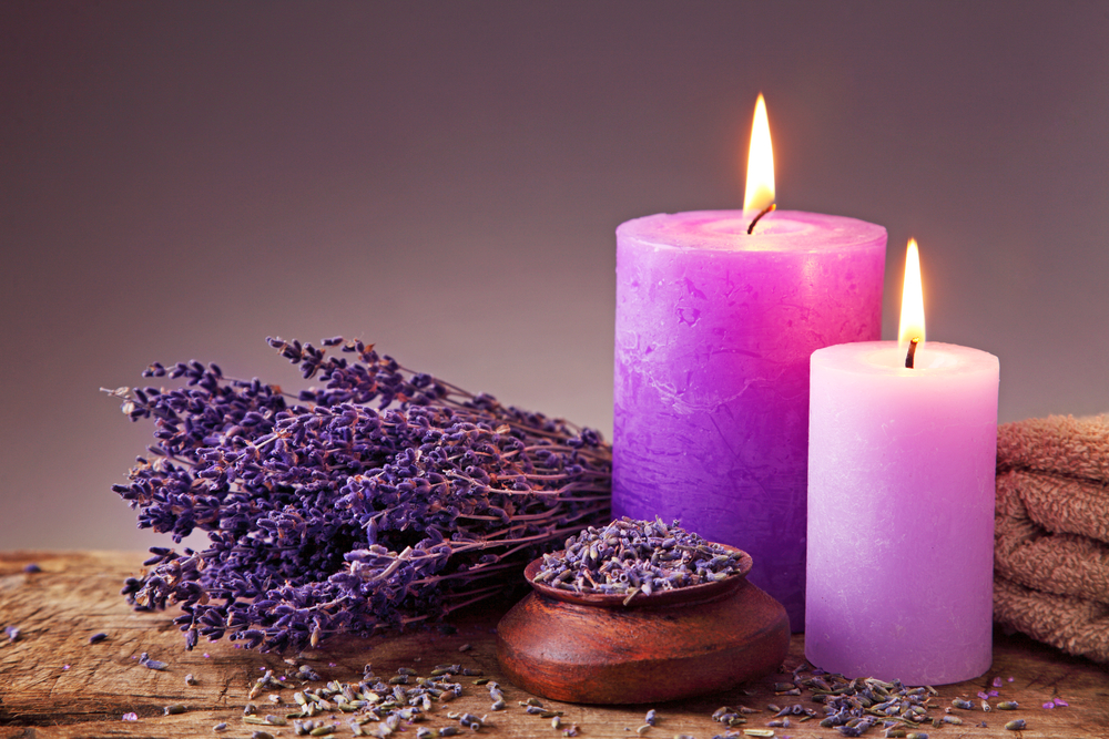 Dos velas color lavansa sobre una mesa de madera junto a un ramo de lavanda y flores de lavanda esparcidas - El Templo de Gala -Tarot