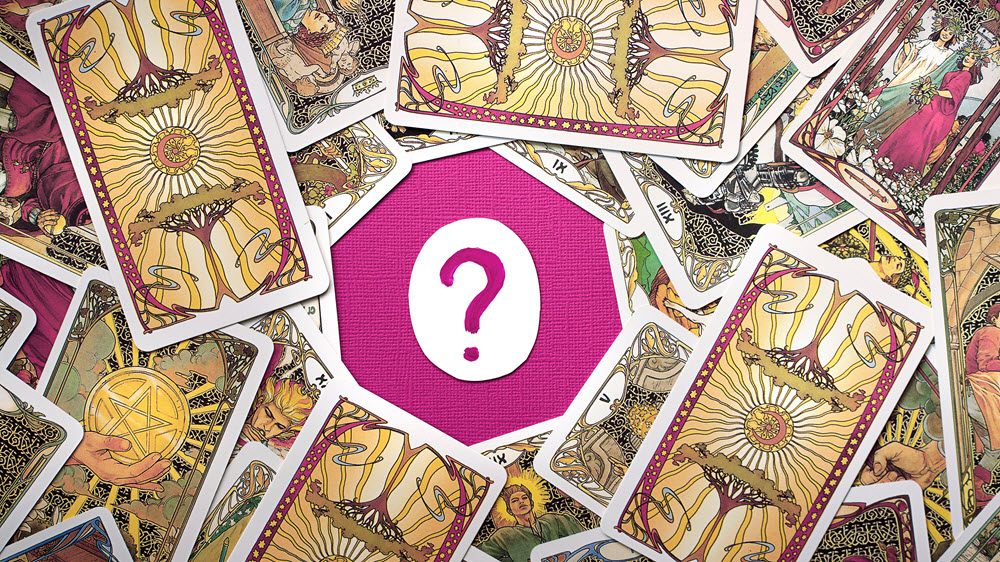 Una mesa fuxia con un papel con una interrogación dibujada en el centro en color fuxia, alrededor hay cartas del tarot con ilustraciones de árboles, estrellas, lunas, personas, mujeres jóvenes con corona naturales de flores, ramas y hojas - El Templo de Gala -Tarot