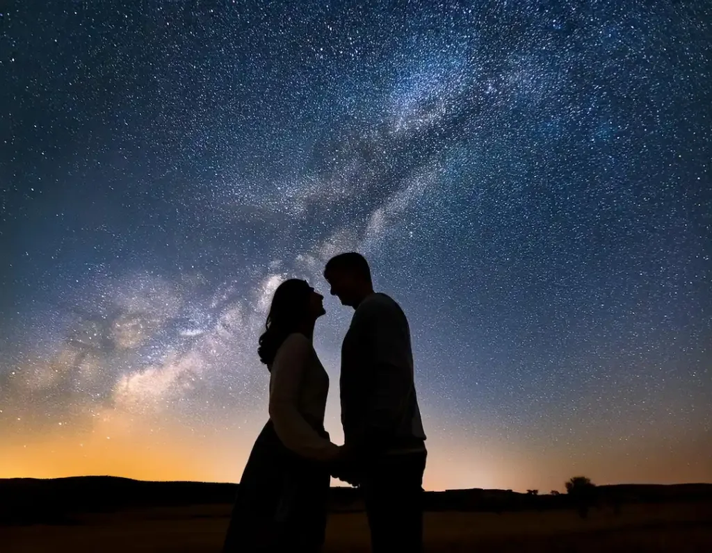 Una imagen en un entorno nocturno estrellado donde se muestra a una pareja mirándose fijamente mientras que demuestran amor y buscan ayuda en el tarot para fortalecerlo | El Templo de Gala | Tarot